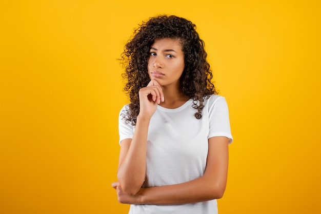 Jovem negra pensando isolado sobre amarelo