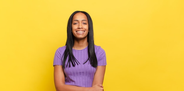 Jovem negra rindo tímida e alegre, com uma atitude amigável e positiva, mas insegura