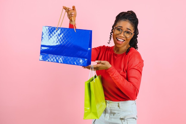 Jovem negra segurando sacolas de compras no fundo rosa