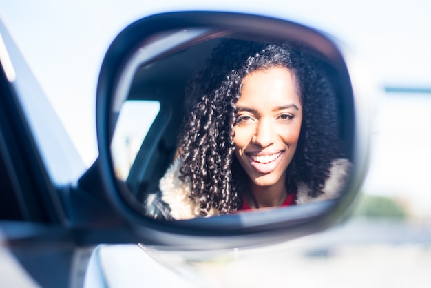 Jovem negra sentada no carro sorrindo