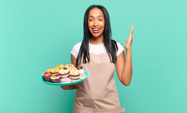 Jovem negra sentindo-se feliz, excitada, surpresa ou chocada, sorrindo e atônita com algo inacreditável. conceito de chef de padaria