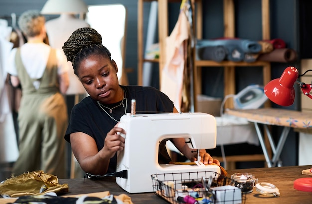 Jovem negra séria em roupas casuais costurando novos trajes da moda