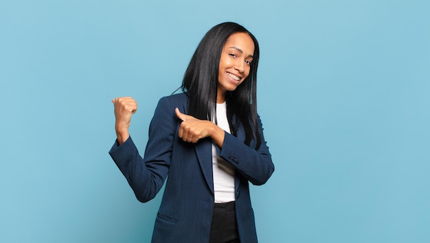 Jovem negra sorrindo alegre e casualmente apontando para copiar o espaço ao lado, sentindo-se feliz e satisfeita. conceito de negócios