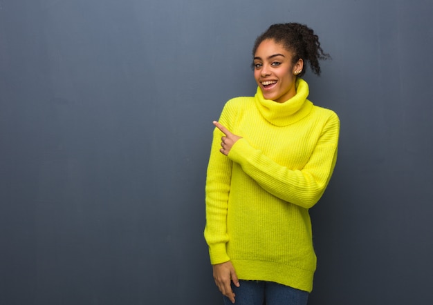 Jovem negra sorrindo e apontando para o lado