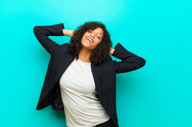 Foto jovem negra sorrindo e se sentindo relaxado, satisfeito e despreocupado, rindo positivamente e relaxando contra a parede azul