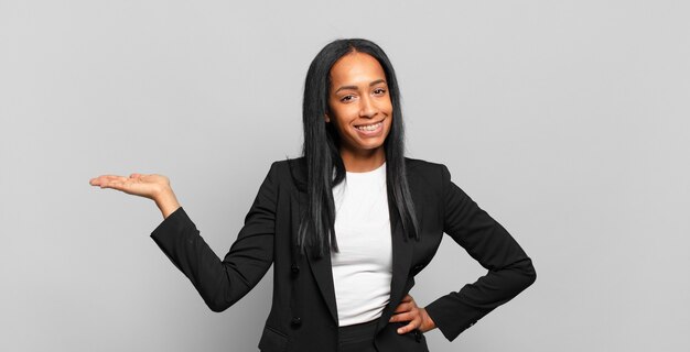 Jovem negra sorrindo, sentindo-se confiante, bem-sucedida e feliz, mostrando o conceito ou ideia no espaço da cópia ao lado. conceito de negócios