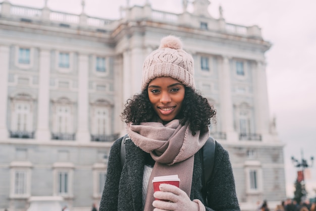 Jovem negra tomando café vagando pelas ruas de Madrid no inverno