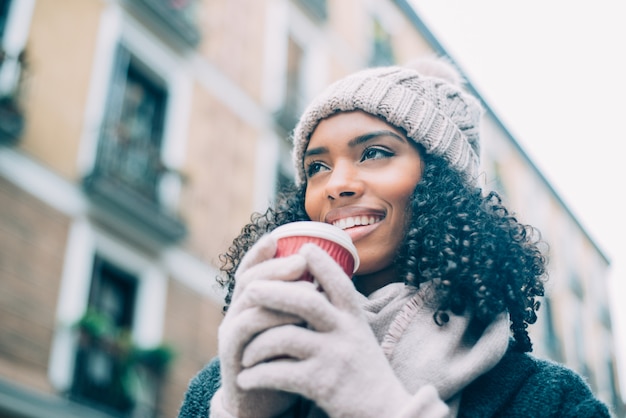 Jovem negra tomando café vagando pelas ruas de Madrid no inverno