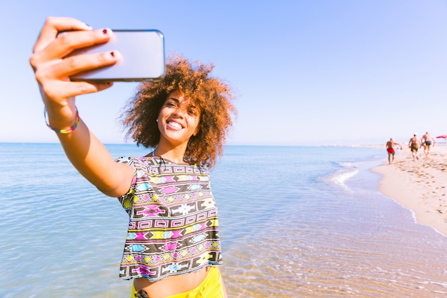 Jovem negra tomando uma selfie na praia