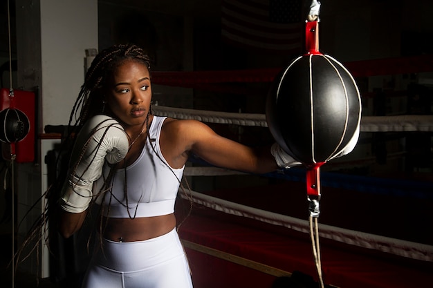 Jovem negra treinando boxe em um ringue.