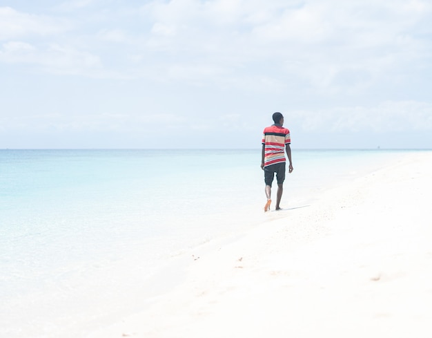 Jovem negro africano caminhando na praia