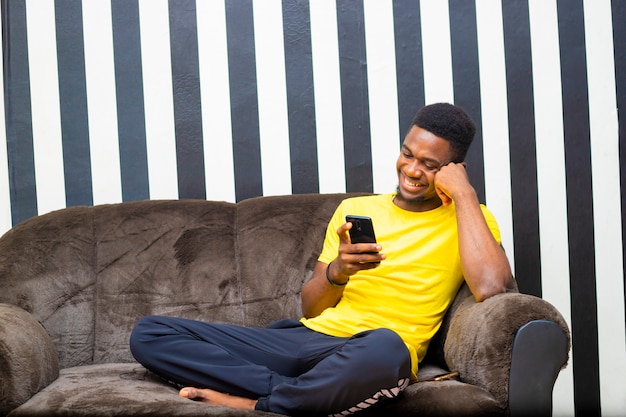 Jovem negro africano comprando de casa usando um dispositivo móvel