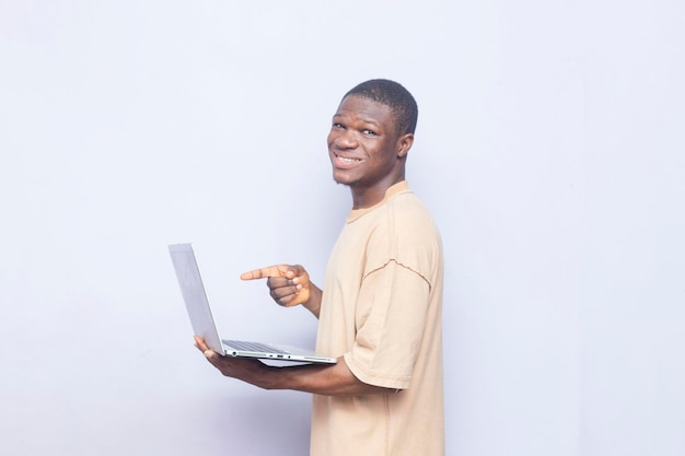 jovem negro africano encantado segurando ponto no laptop com um dedo, conceitos de tecnologia feliz