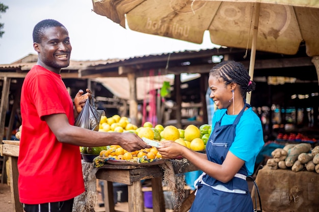 Jovem negro africano pagando mercearia em um mercado africano local