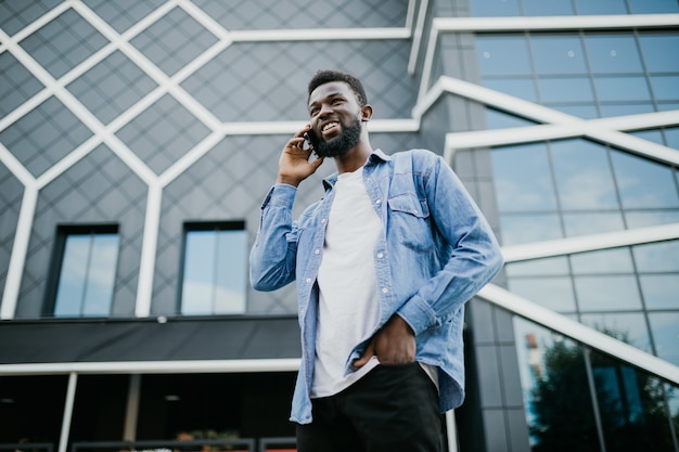 Foto jovem negro africano sorrindo e falando no celular lá fora