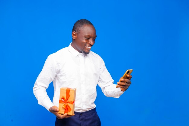 Jovem negro africano vestido casualmente sorrindo olhando para o celular