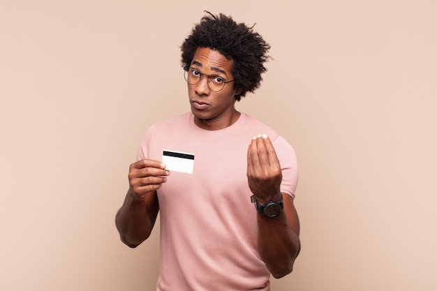 Jovem negro afro fazendo capice ou gesto de dinheiro, mandando você pagar suas dívidas!