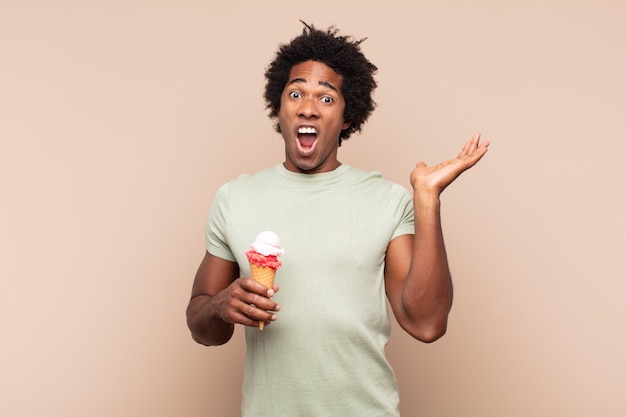 Jovem negro afro se sentindo feliz, animado, surpreso ou chocado, sorrindo e surpreso com algo inacreditável