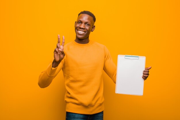 Jovem negro americano africano contra a parede laranja, segurando um cartaz