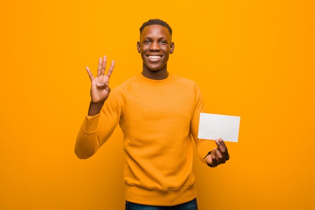 Jovem negro americano africano contra a parede laranja, segurando um cartaz