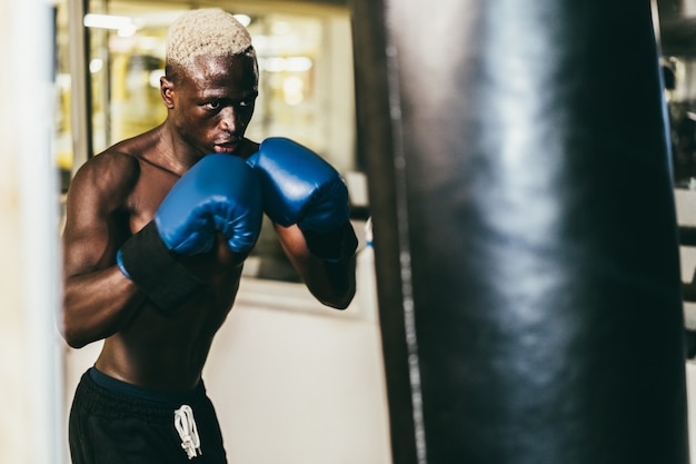 Jovem negro boxe dentro do clube de treinamento de fitness - foco no rosto