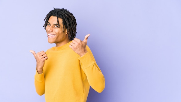 Jovem negro com penteado rasta levantando os dois polegares, sorrindo e confiante