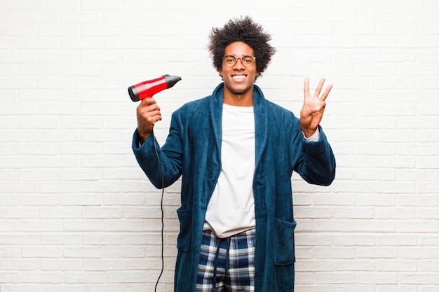 Jovem negro de pijama com um secador de cabelo