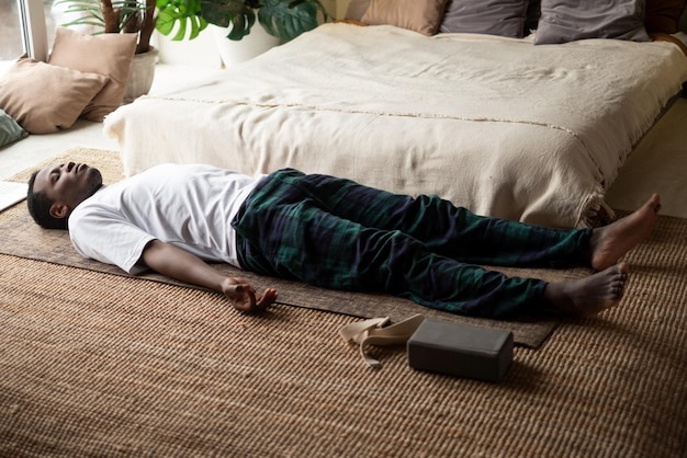 Jovem negro deitado em exercício de corpo morto ou pose de cadáver com os olhos fechados Savasana pose malhando descansando após o treino
