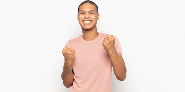 Jovem negro gritando triunfantemente, rindo e se sentindo feliz e animado enquanto festeja o sucesso