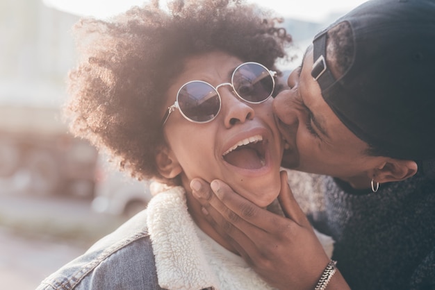 Jovem negro lindo beijando na bochecha sua namorada