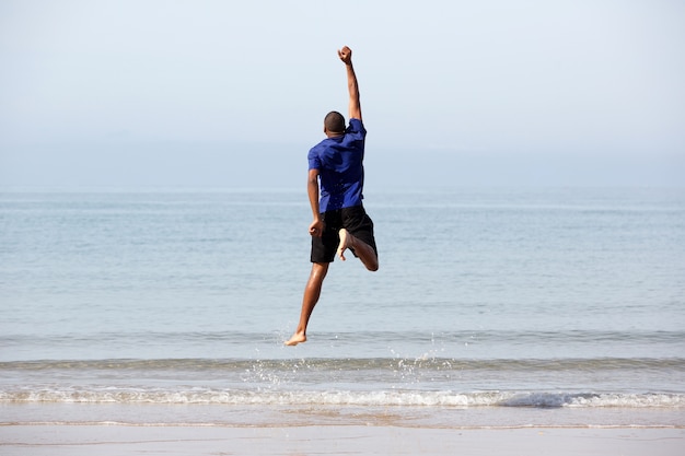 Jovem negro pulando na praia