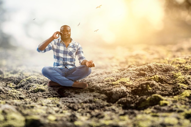 Jovem negro sentado e meditando. Mídia mista