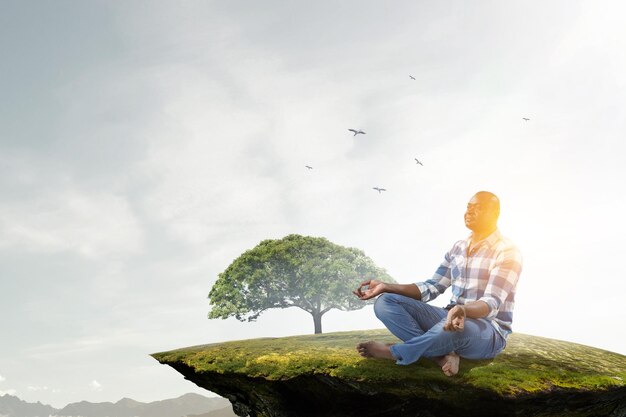 Jovem negro sentado e meditando. Mídia mista