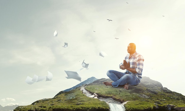 Jovem negro sentado e meditando. Mídia mista