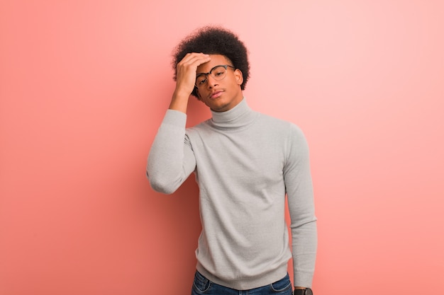 Jovem negro sobre uma parede rosa cansado e com muito sono