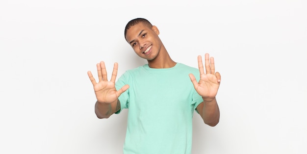 Foto jovem negro sorrindo e parecendo amigável, mostrando o número nove ou nono com a mão para a frente, em contagem regressiva