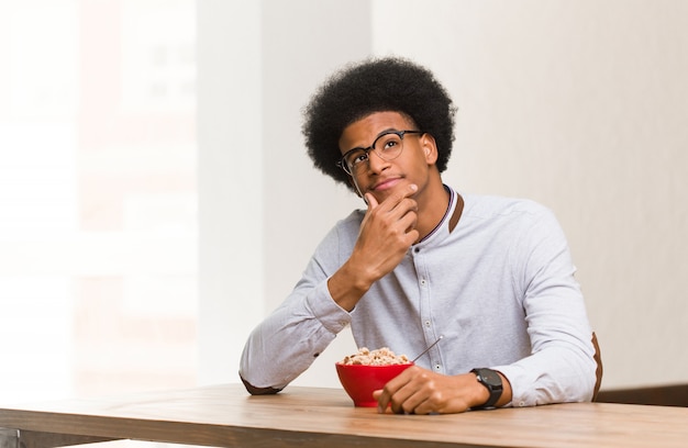 Jovem negro tomando um café da manhã duvidoso e confuso