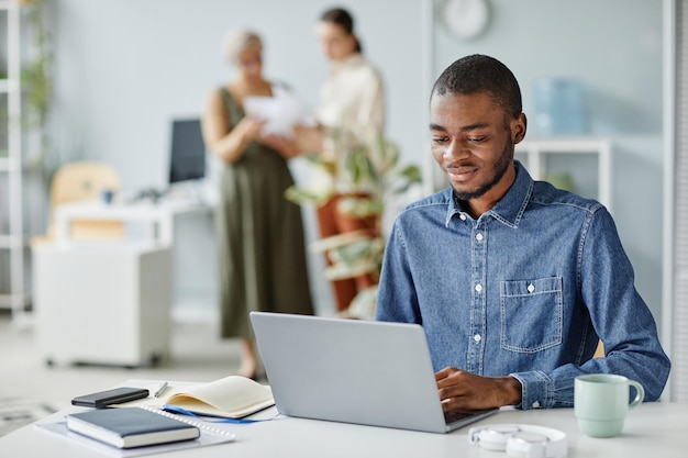 Jovem negro usando laptop no local de trabalho mínimo