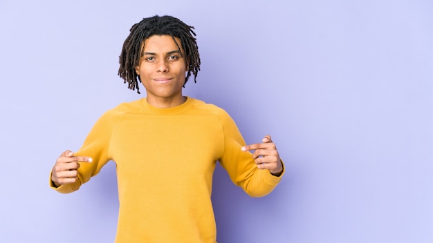 Jovem negro usando penteado rasta pessoa apontando com a mão para um espaço de cópia de camisa, orgulhoso e confiante