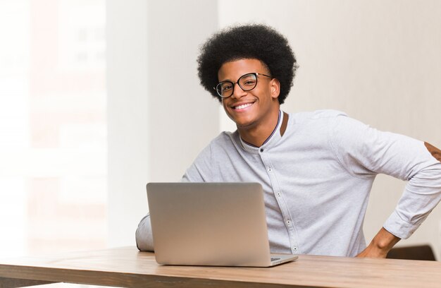 Jovem negro usando seu laptop com as mãos nos quadris