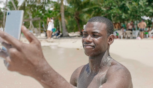 Jovem negro usando smartphone perto das ondas do mar