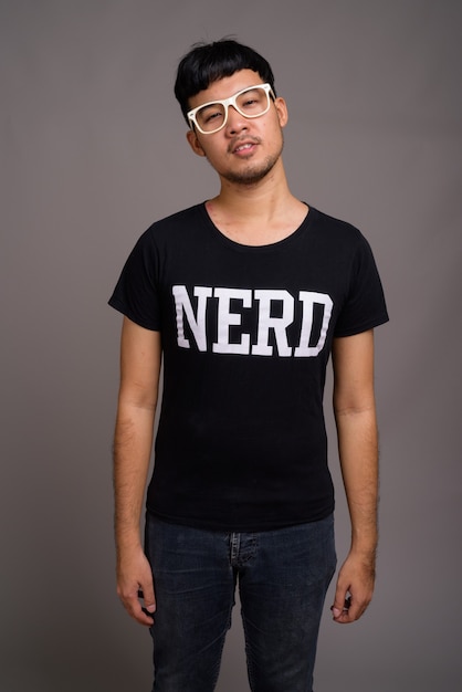 Jovem nerd asiático usando óculos contra o cinza