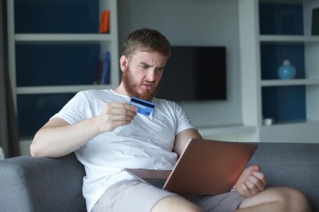Jovem nervoso, triste, chateado, confuso, estressado, preocupado, com problemas para pagar compras online.