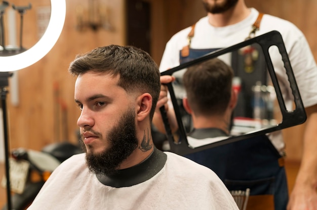 Jovem no barbeiro verificando novo corte de cabelo