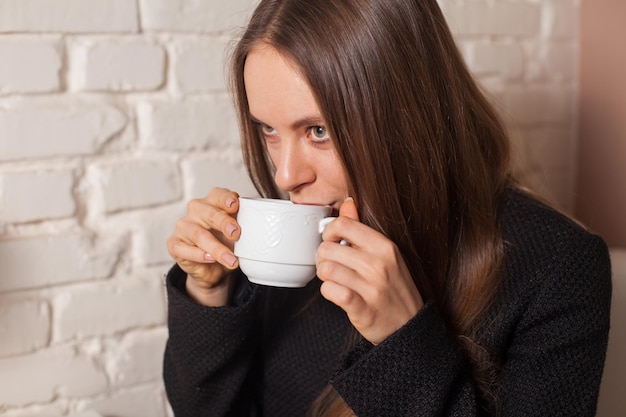 Jovem no café bebendo aqui bebida favorita chá em copo branco