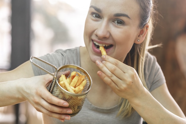 Jovem no café come batatas fritas