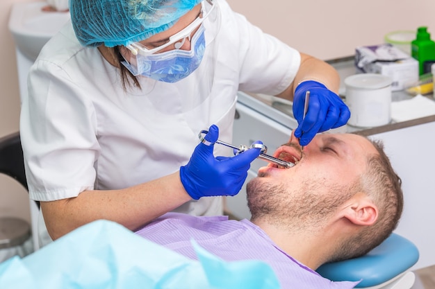 Jovem no consultório odontológico fazendo exame odontológico pelo dentista