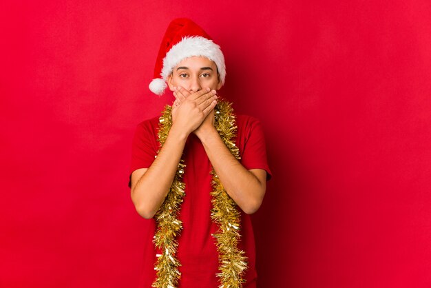 Jovem no dia de Natal chocado cobrindo a boca com as mãos.