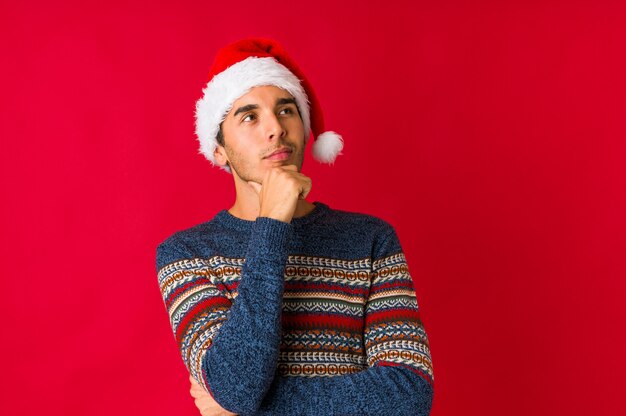 Jovem no dia de Natal cobre os olhos com as mãos, sorri amplamente esperando por uma surpresa.