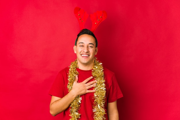 Jovem no dia de natal ri alto, mantendo a mão no peito.